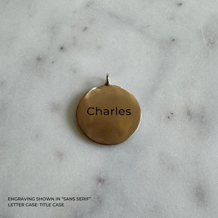 A large round bronze pendant engraved with the name &