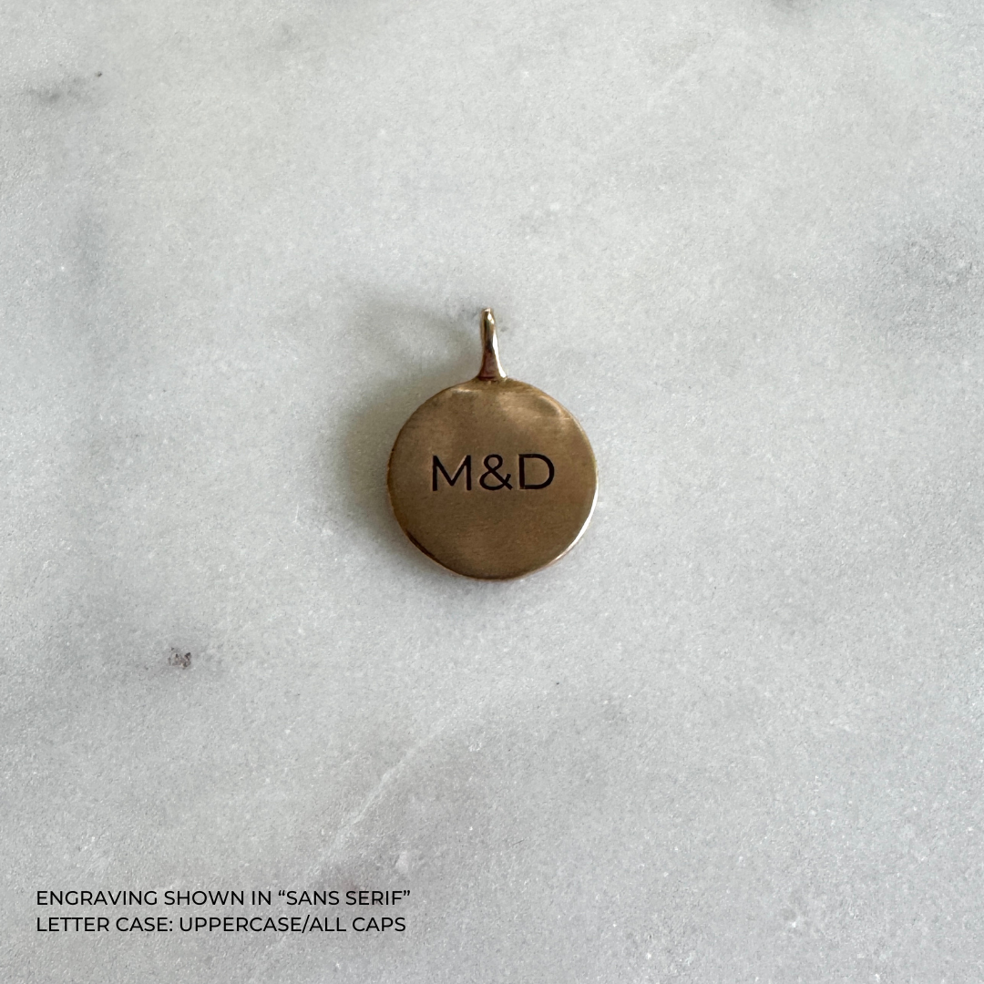A round bronze pendant with the engraved letters &