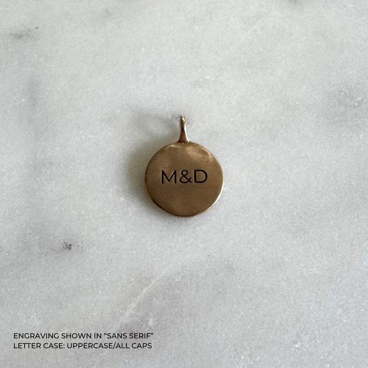 A round bronze pendant with the engraved letters &