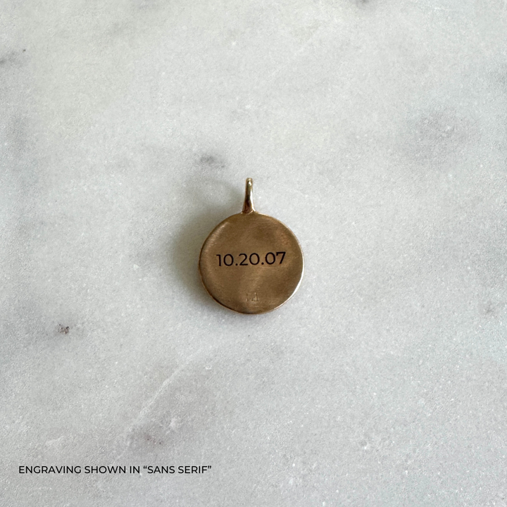 A small round bronze pendant engraved with the date &
