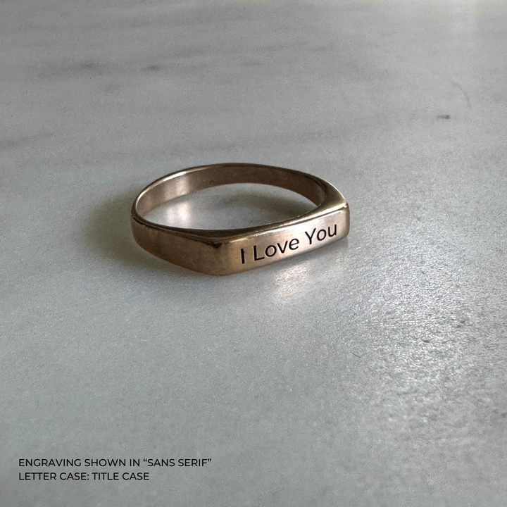 A bronze signet-style ring engraved with the words &