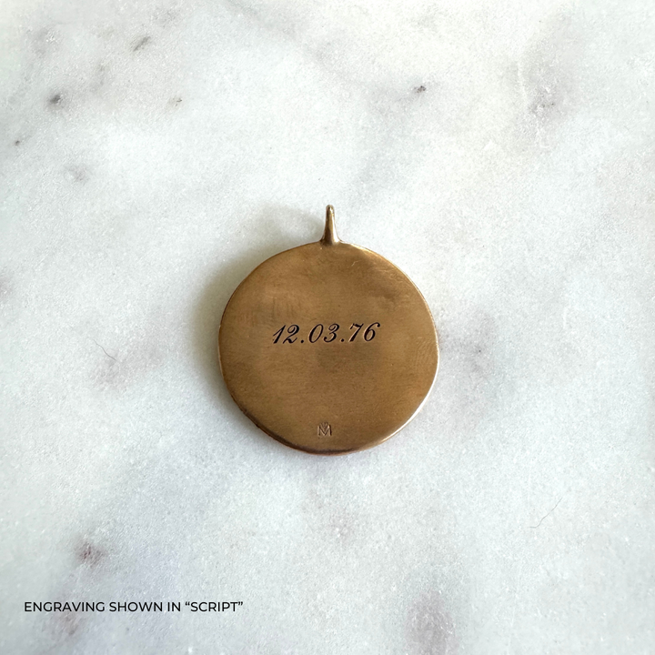 A large round bronze pendant engraved with the date &