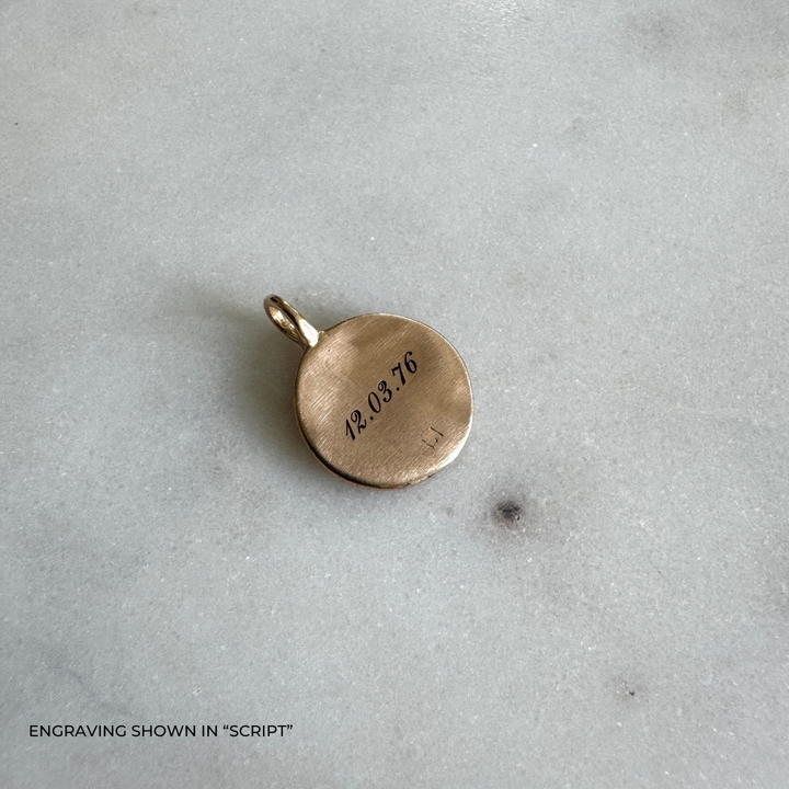 A round bronze pendant engraved with the date &