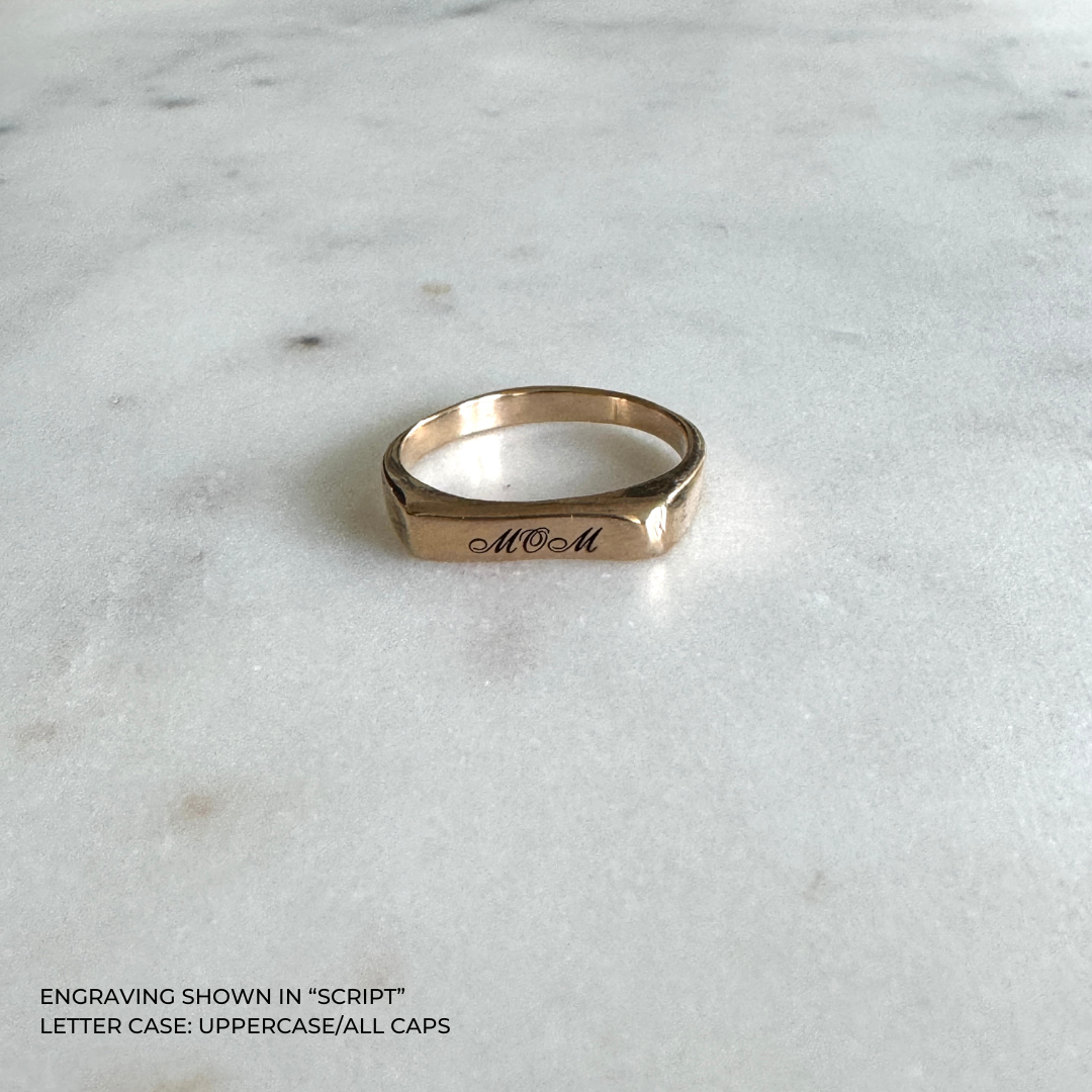 A bronze signet-style ring engraved with the word &