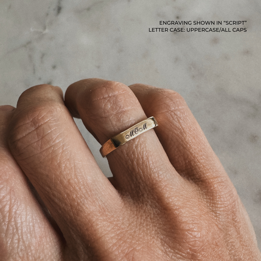 A bronze signet-style ring engraved with the word &