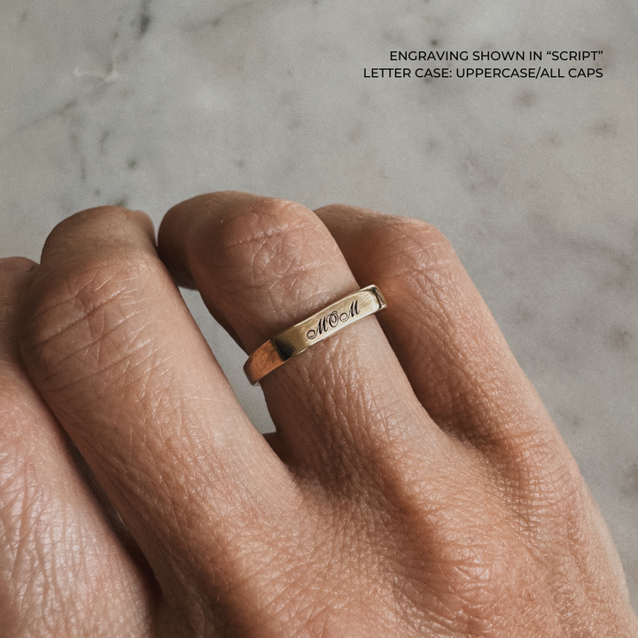 A bronze signet-style ring engraved with the word &