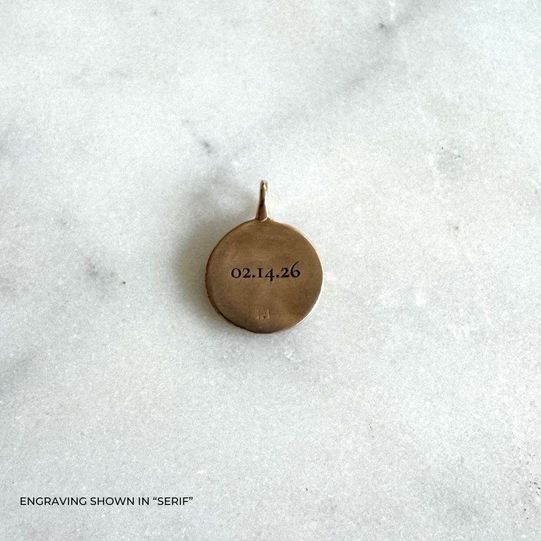 A small round bronze pendant engraved with the date &