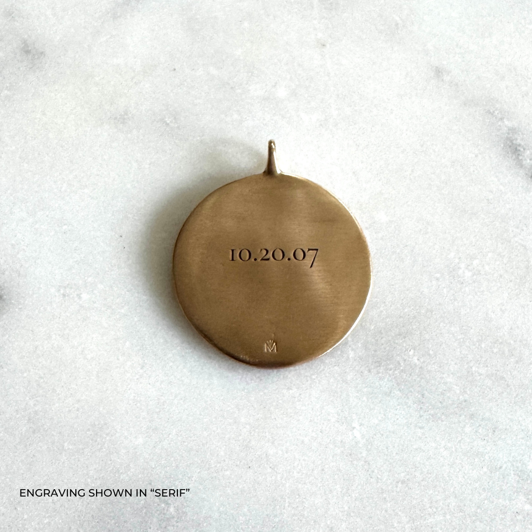 A large round bronze pendant engraved with the date &