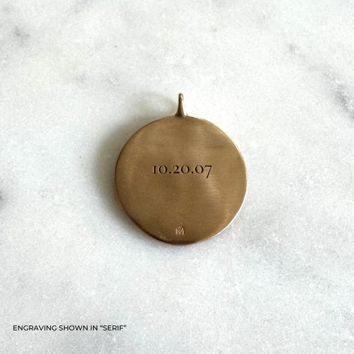 A large round bronze pendant engraved with the date &