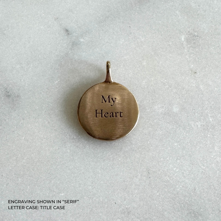 A round bronze pendant engraved with the words &
