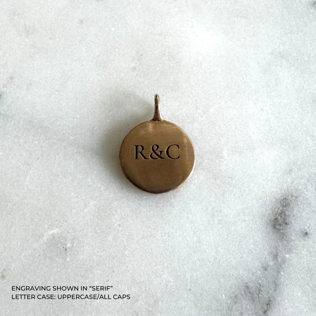 A round bronze pendant with the engraved initials &