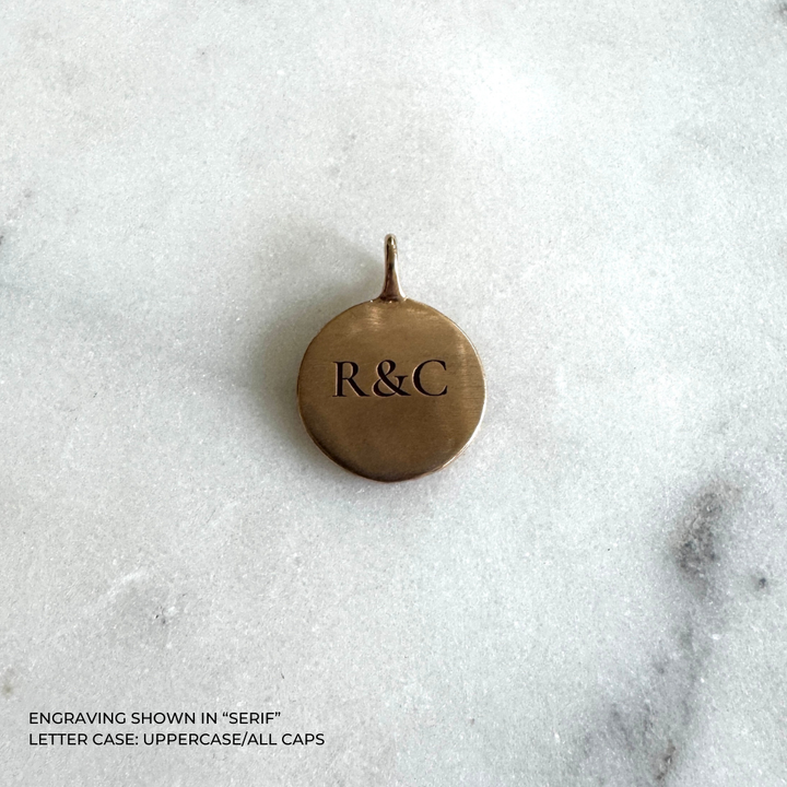 A round bronze pendant with the engraved initials &