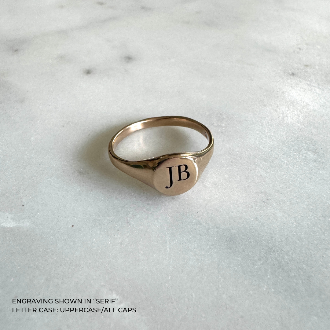 A bronze signet-style ring engraved with the initials &