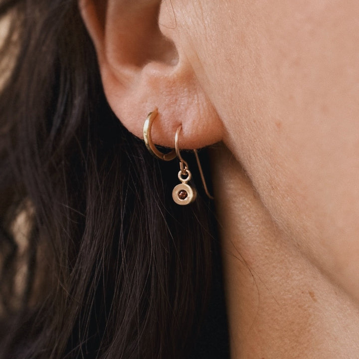 Close up of a person wearing bronze garnet earrings | MIMOSA Handcrafted