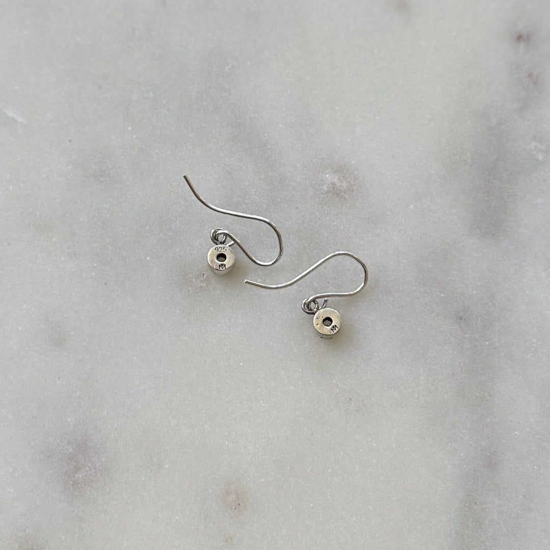 Pair of silver grace birthstone earrings on a marble surface | MIMOSA Handcrafted