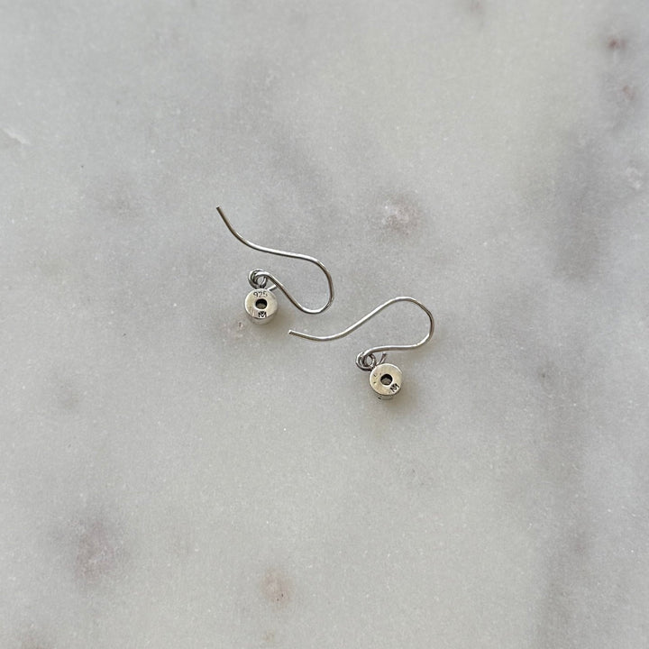 Pair of silver grace birthstone earrings on a marble surface | MIMOSA Handcrafted
