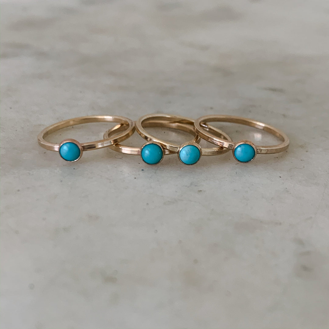 Four Dainty Gold Rings with One Small Blue Turquoise Stone lined up next to each other