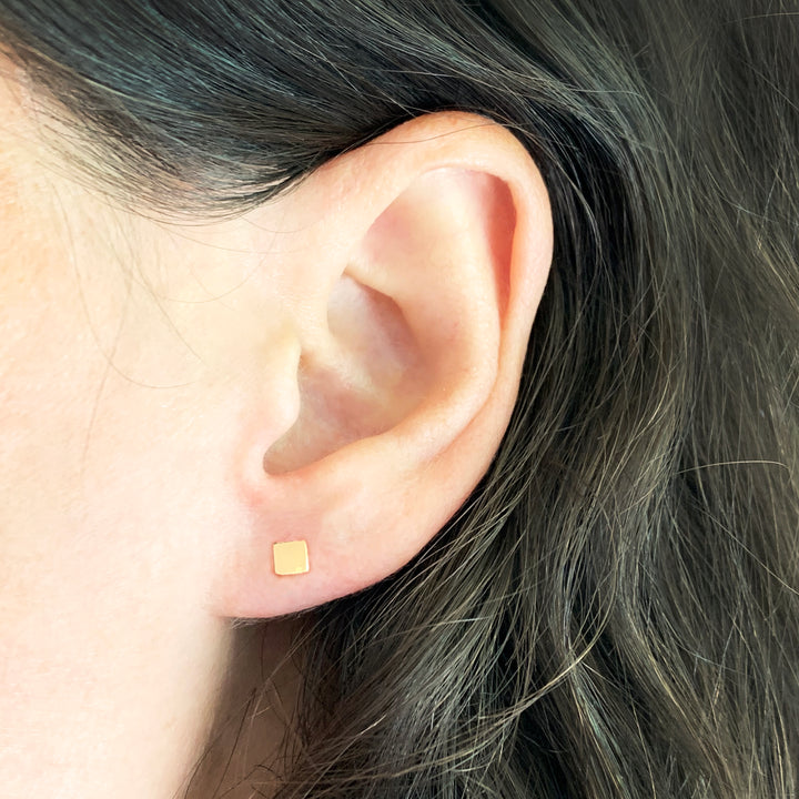 Woman wearing gold-filled square stud earrings